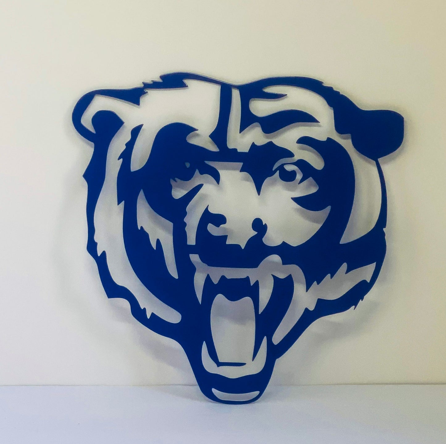 blue bear face metal sign on white wall 